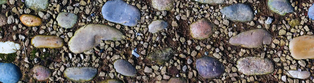 Earth element banner: colourful stones placed like treasures on a path, uncovered by time